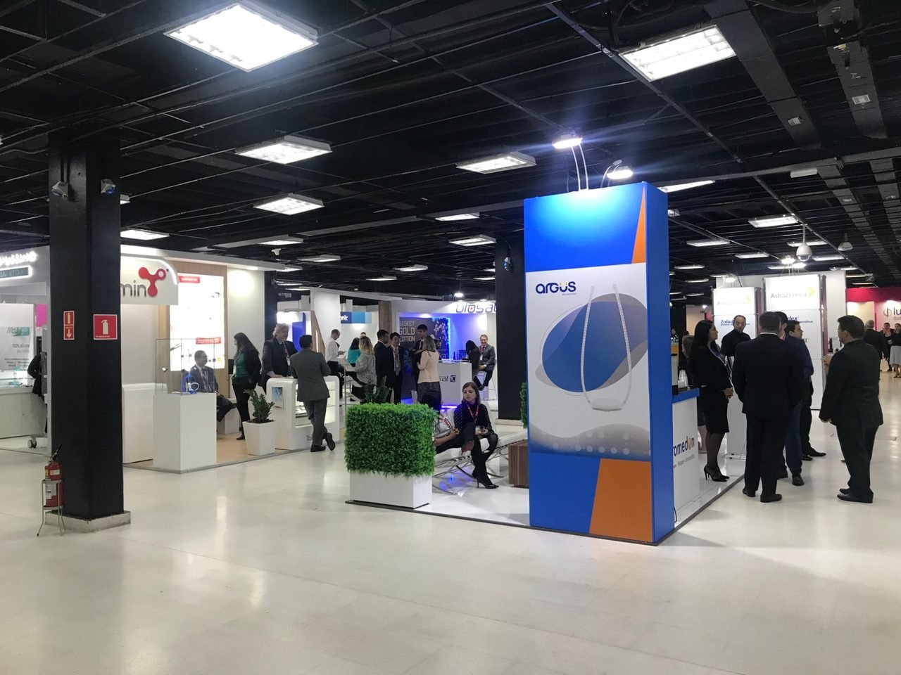 Corredor de feira com estandes e executivos conversando em evento de negócios
