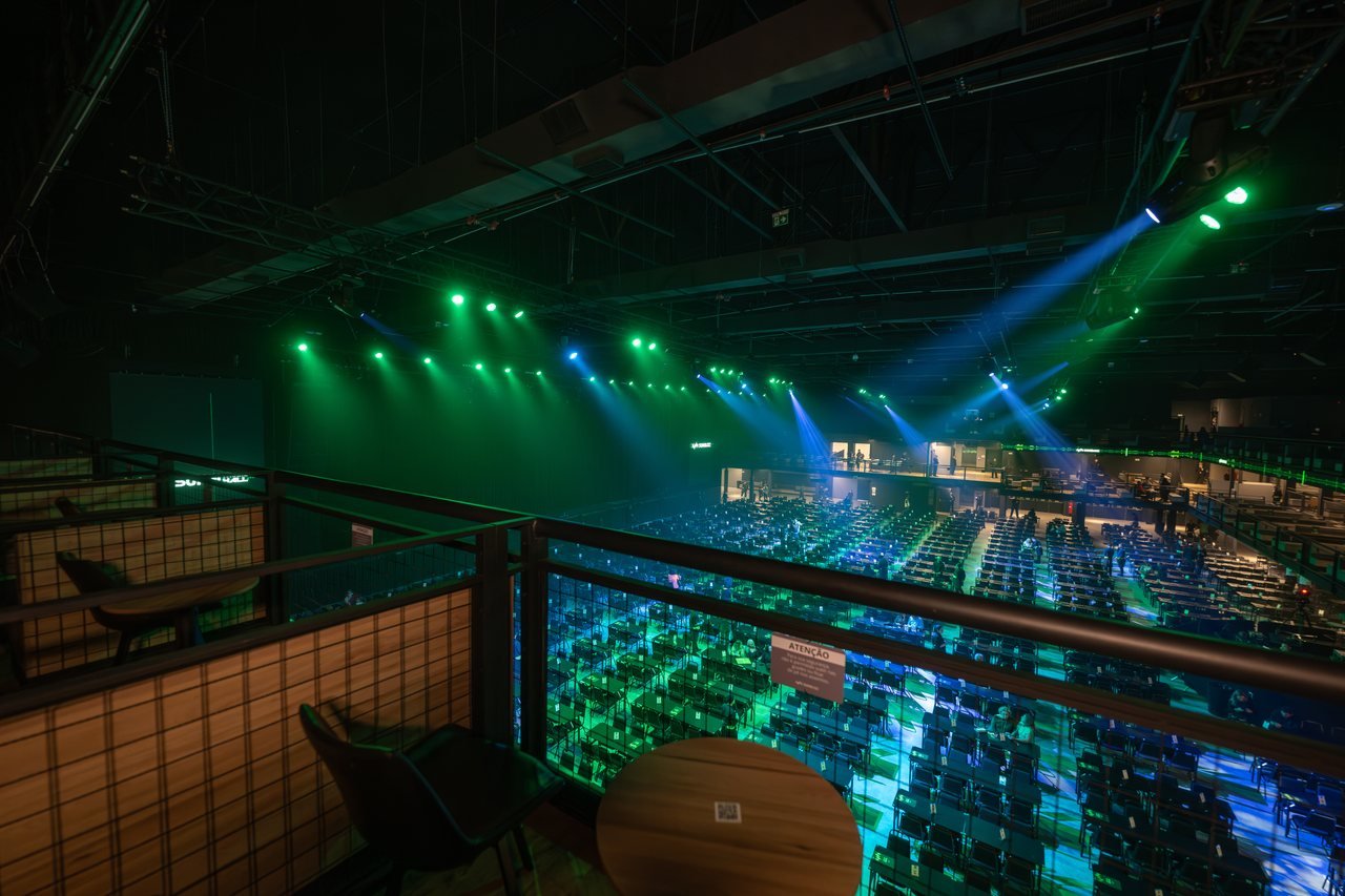 Suhai Music Hall montada para show, com iluminação verde sobre as mesas